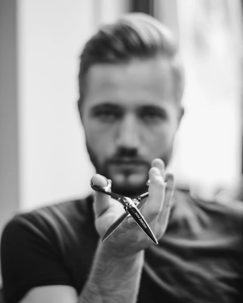 Luka, barber drži škare uperene prema kameri.