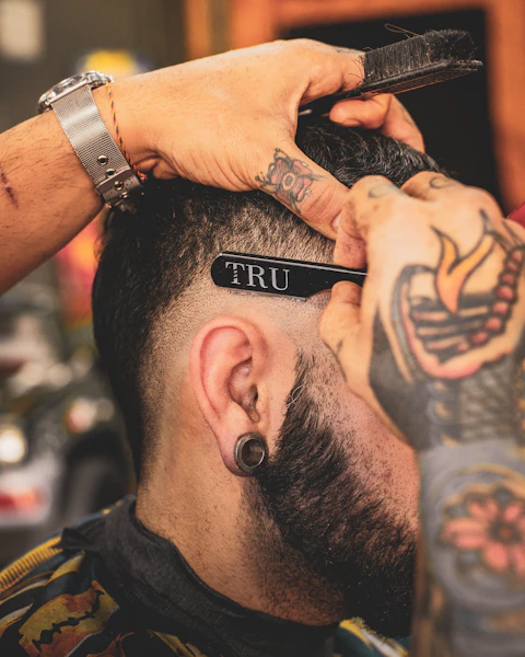 Barber s tetovažama radi precizan fade uz češalj.